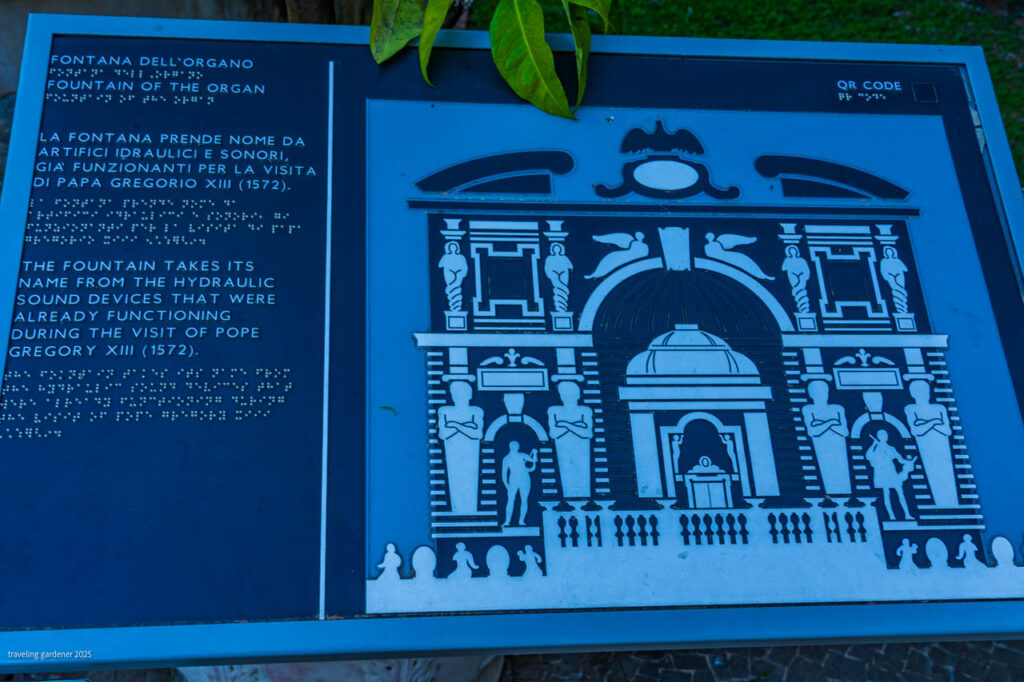 Blue informational plaque about Fontana dell'Organo with English and Italian text and a stylized fountain illustration beside a door-like façade panel.