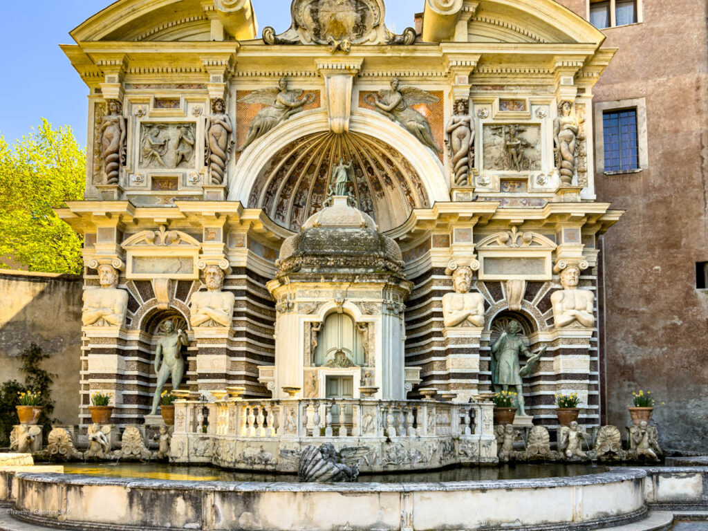 Ornate historic fountain with carved statues, arches, and a central domed niche.