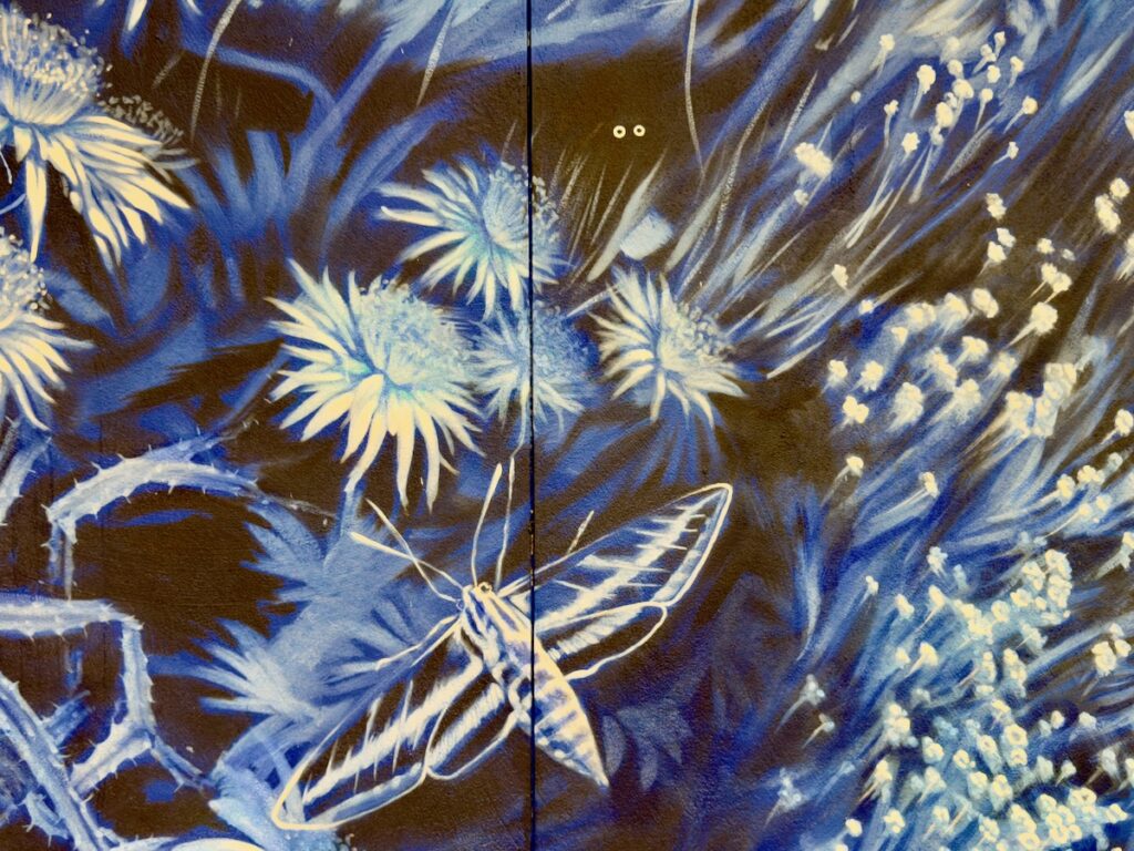 Blue-toned mural of abstract flowers with a white butterfly in the center.