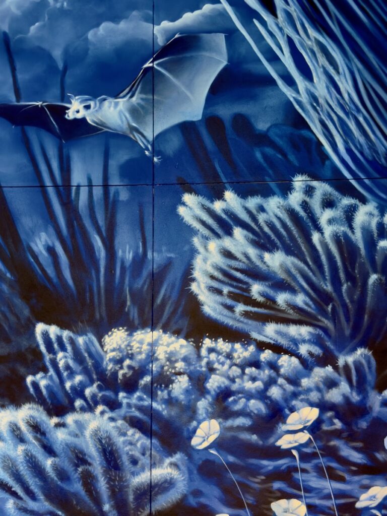 Blue underwater mural showing a manta ray gliding over coral and sea plants in deep blue tones.
