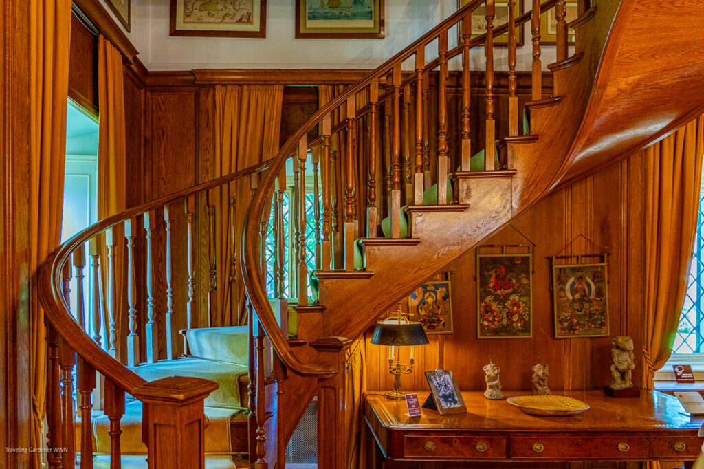 Curved wooden staircase in a richly paneled room with a desk and vintage decorations.